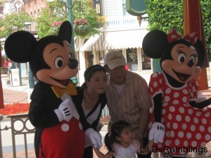 Mickey Mouse and Minnie Mouse characters posing for a picture with an Asian family
