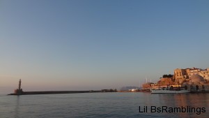 A view over water of the Greek town by the long walk to a lighthouse.