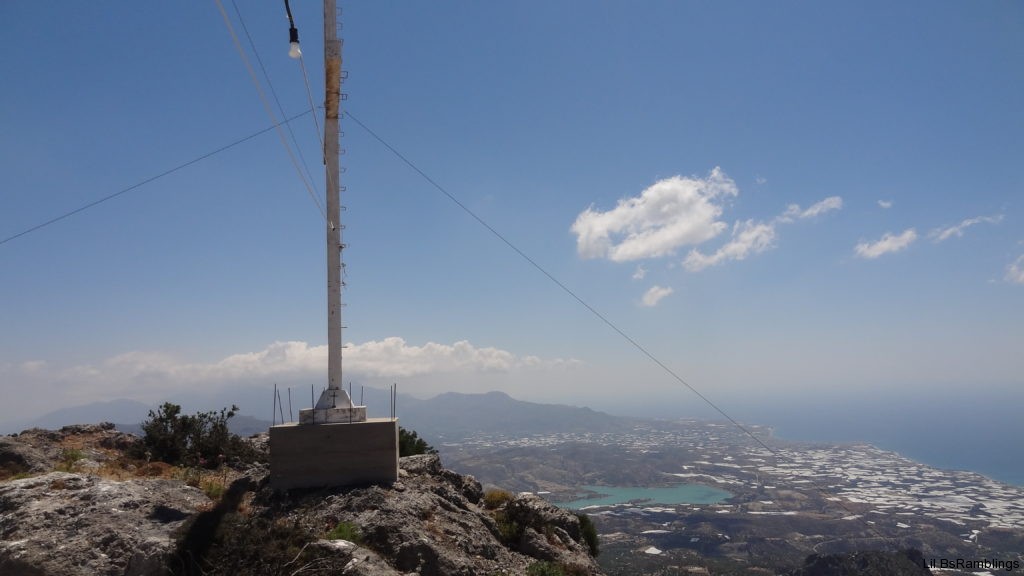 The bottom of a huge white cross faces the city on the island far below the mountain it stands on.