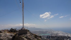 The bottom of a huge white cross faces the city on the island far below the mountain it stands on.